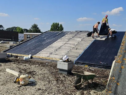 Workers installing a sloped roof on a school building