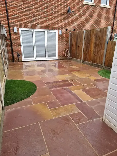 New decorative stone patio layed in a back garden, with grass features