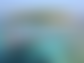 A large tour boat is docked at a long jetty leading to a small tropical island, surrounded by shallow clear water and exposed reef flats with people visible on the beach