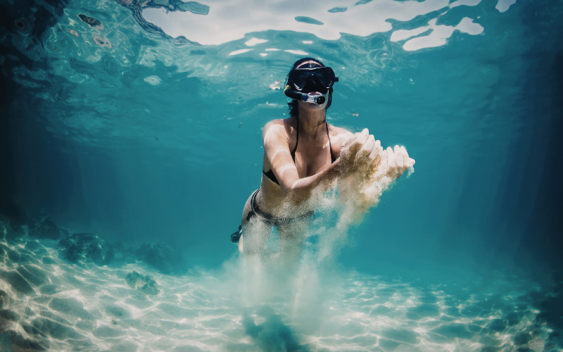 A snorkeler diving underwater with a diving mask in the clear shallow waters of the Great Barrier Reef