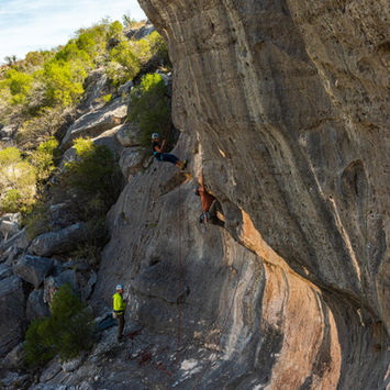 Climber scaling challenging rock face