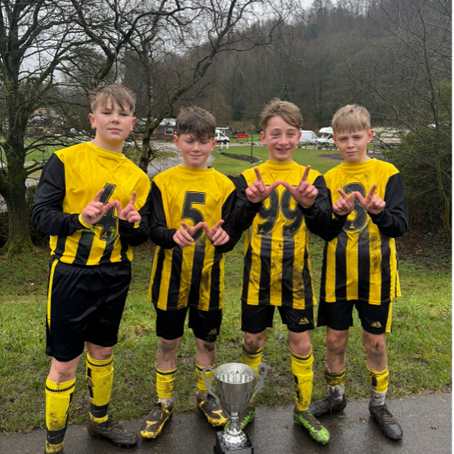 Four young footballers with a trophy