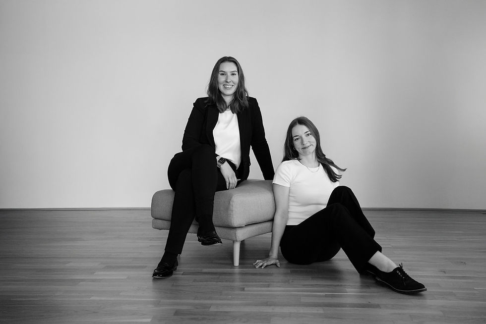 Ein Teamfoto von Kreativviertel. Zu sehen sind zwei Frauen, die auf und neben einem tiefgelegenen Sofaelement sitzen.