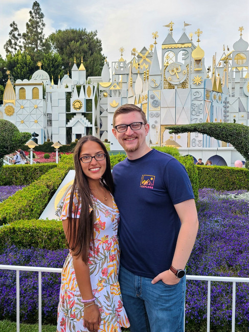DLT! posing in front of the detailed exterior of It's a Small World ride at Disneyland Park
