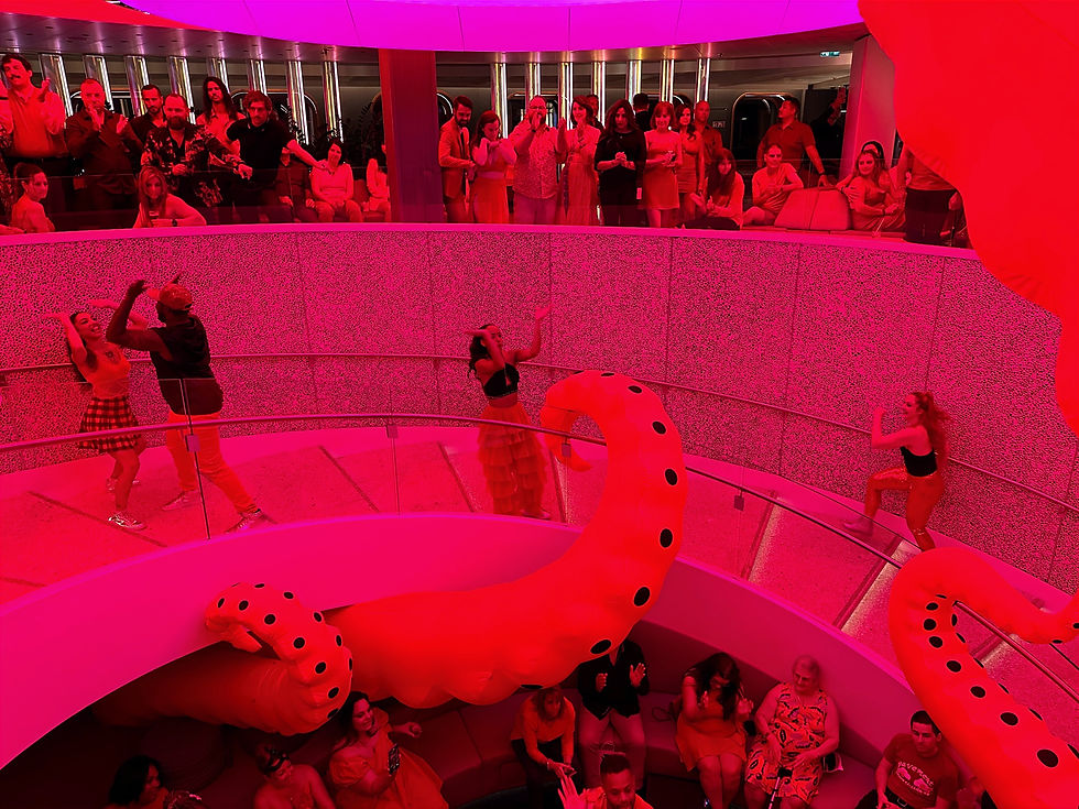 Los bailarines de Happenings Crew y Virgin Voyages bailan durante la Noche Escarlata en la escalera de caracol.