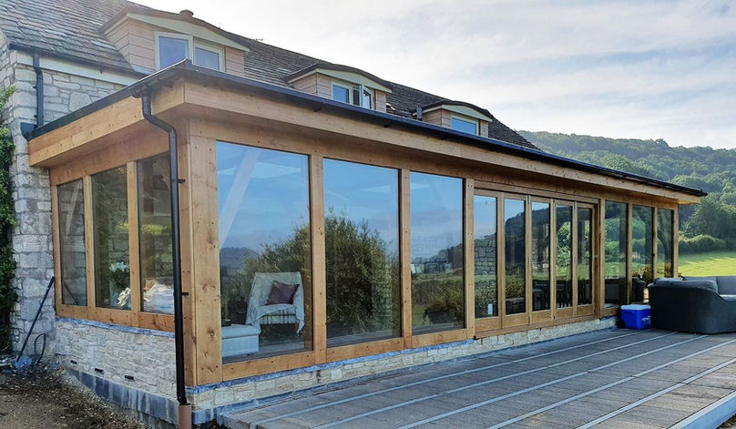 Oak framed glass extension on a stone house with deck