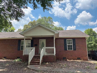 Brick home exterior with front porch and mature trees, Charlotte NC before renovation