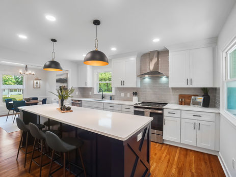 Luxury kitchen with dark island, pendant lighting, and white cabinetry