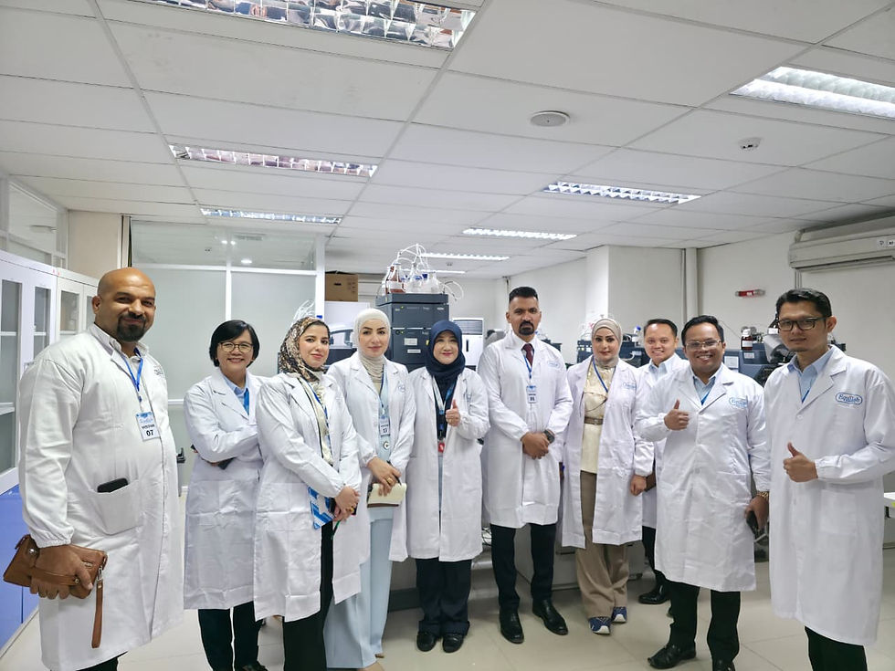 Group of scientists in white lab coats pose in a bright laboratory, smiling and giving thumbs up.
