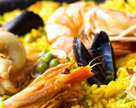 Close-up of a vibrant seafood paella, featuring shrimp, mussels, and squid over saffron-infused rice, highlighting a traditional Spanish dish.