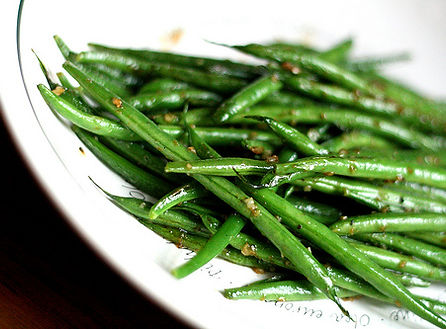 Plate of sautéed green beans seasoned with garlic and spices, offering a simple and healthy vegetable side dish.