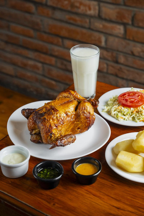 1. Pollo a la brasa entero dorado en mesa roja navideña con arroz verde y ensalada - El Brasero restaurante Quito Ecuador