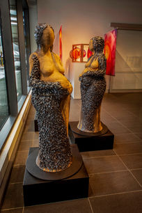 Three life-size Womb Women sculptures by Lisa Corston in gallery window, one gazing outward, Red Thread exhibition, Te Auaha Gallery, Wellington.
