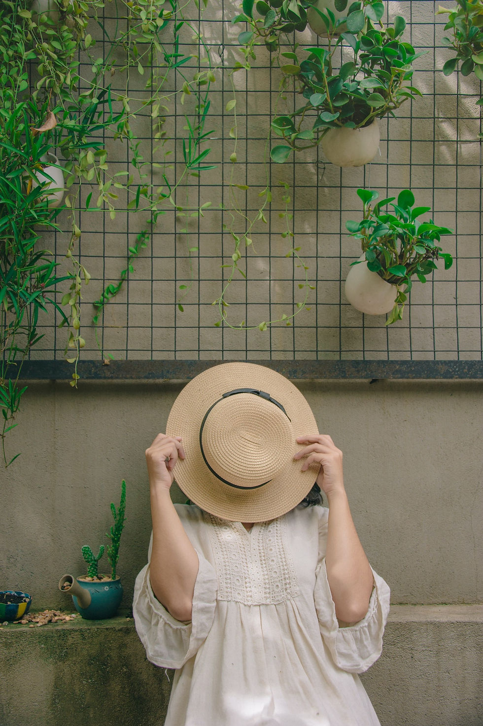 Woman in white dress, with face covered behind brown hat