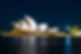 Sydney Opera House illuminated at night with calm harbor waters. Sydney.