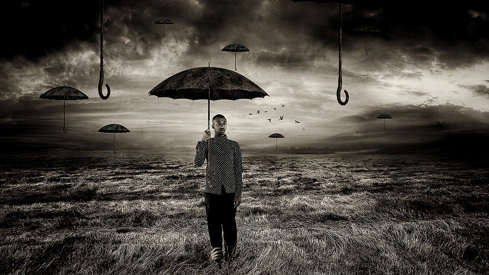 A lone figure holding an umbrella in an open outdoor setting, captured in black and white, evokes stillness, solitude, and silent reflection.