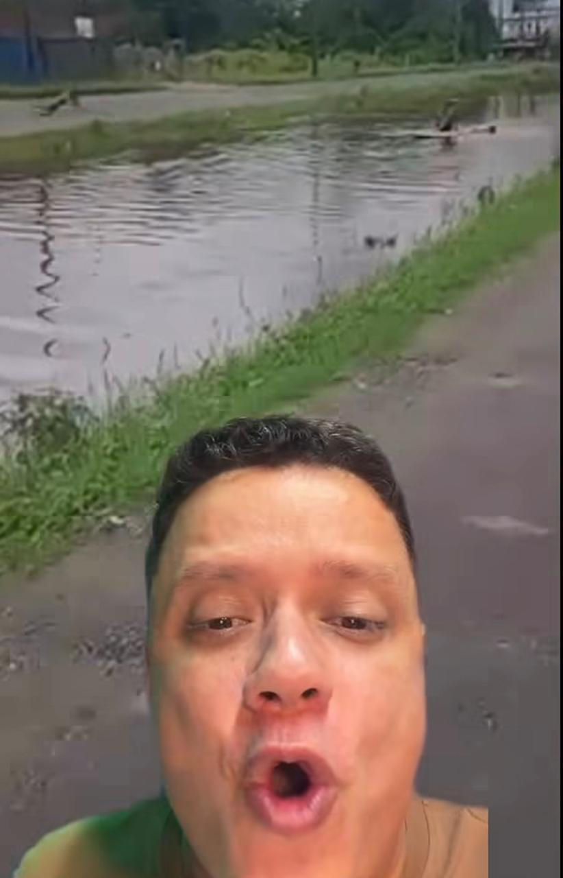 Crianças brincam com prancha em um canal alagado no bairro da Pedreira em Guarujá 