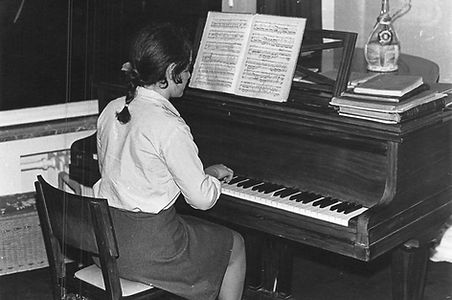 Evelyne practicing the piano as a young girl