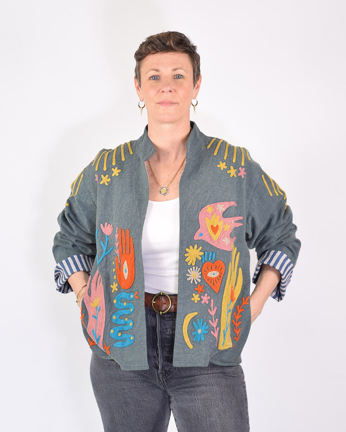 person wearing a blue lightweight jacket with colorful icons embroidered on it