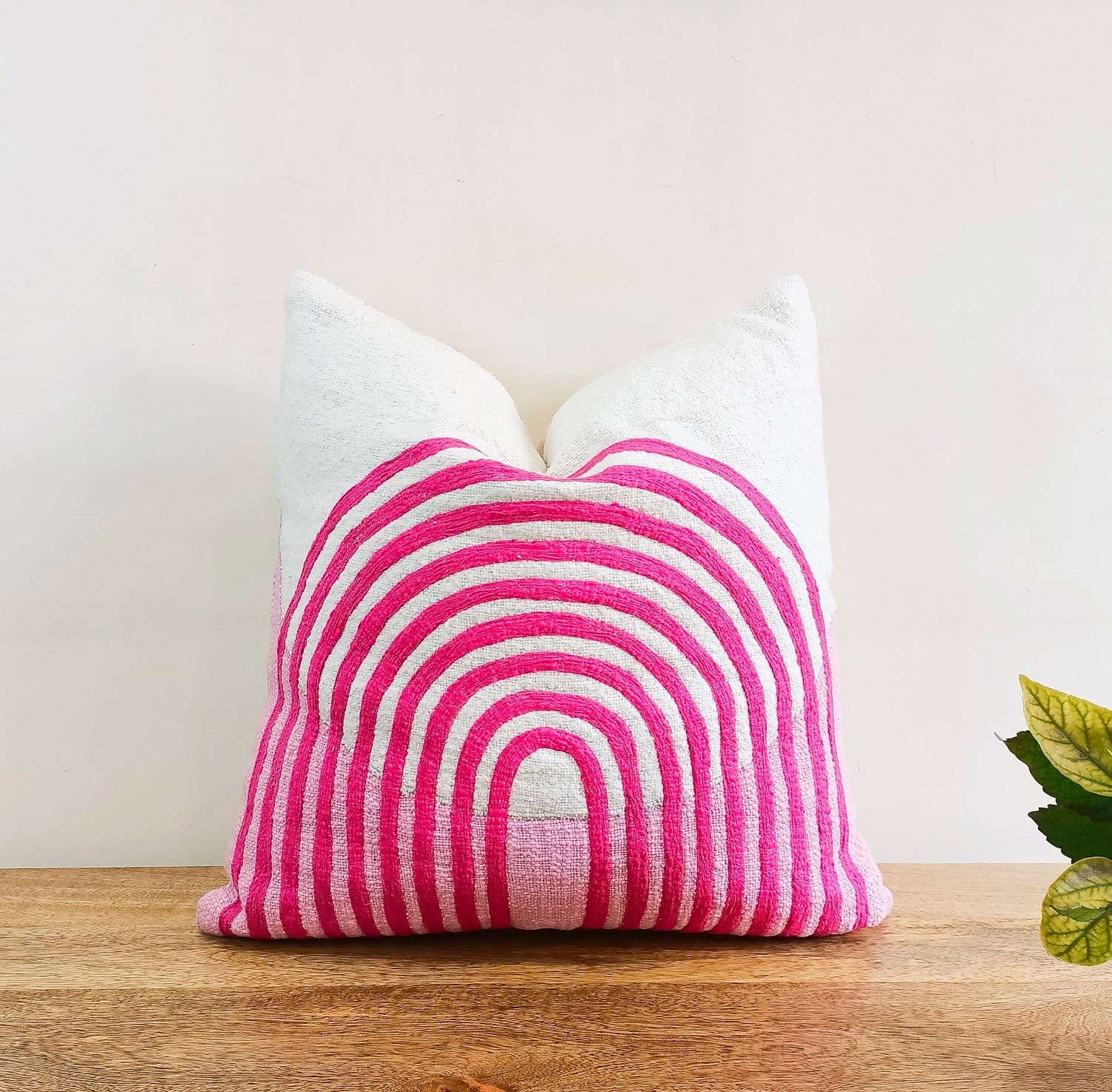 White pillow with pink embroidered rainbow design