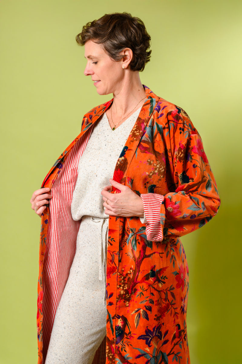 person wearing plush velvet robe with red striped lining