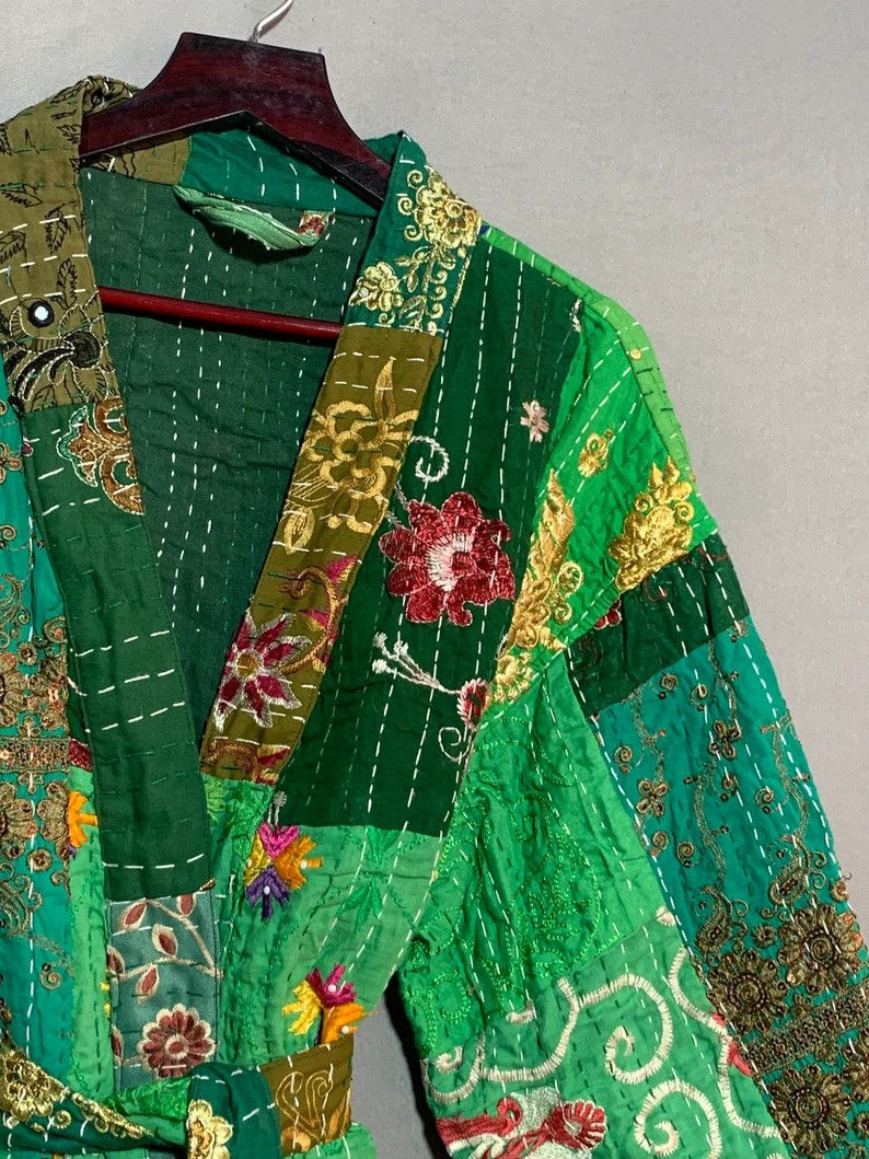 green patchwork kantha stitch robe hanging from a wall