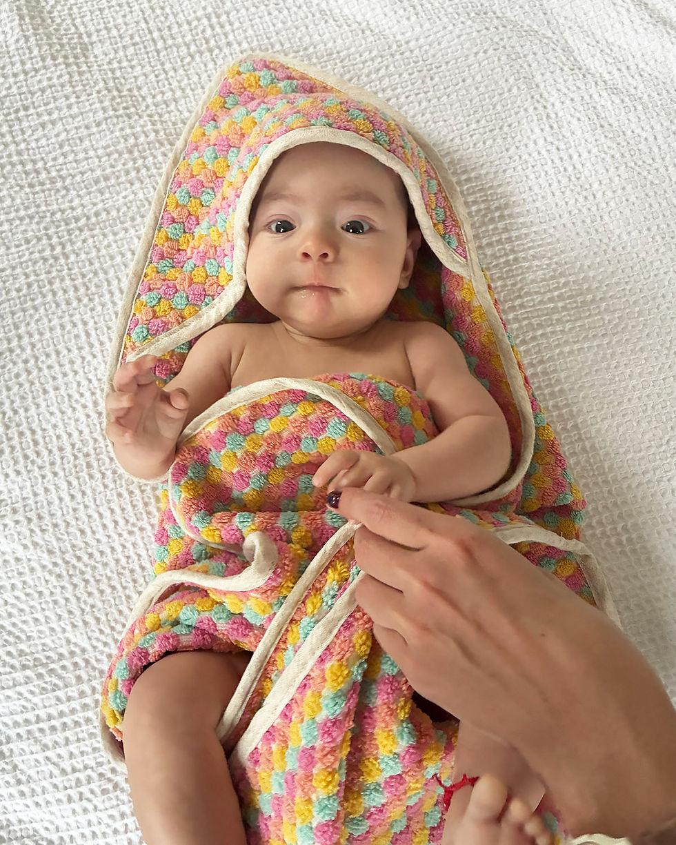 cute baby wrapped in a pastel colored terry cloth blanket