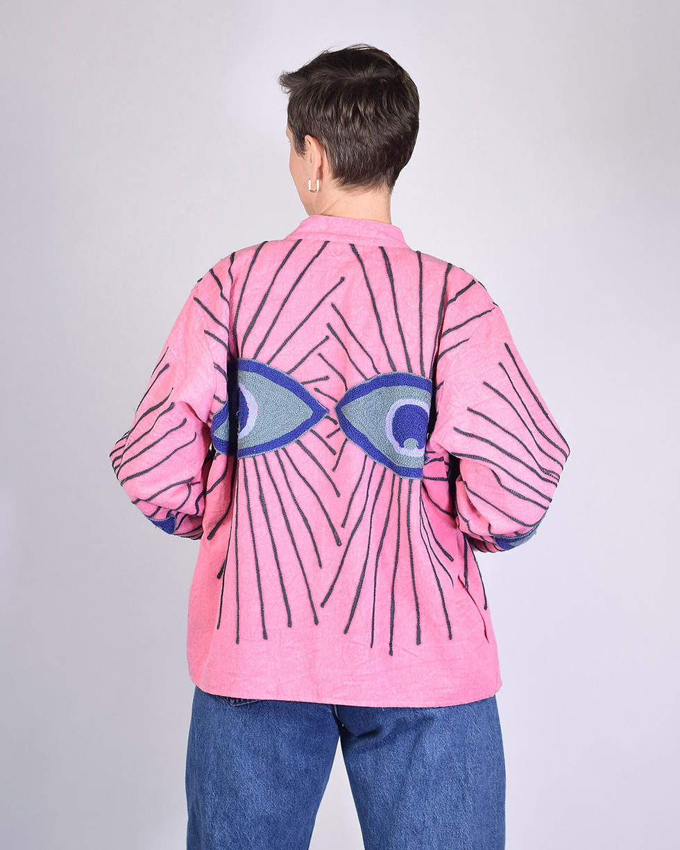 Person wearing pink canvas jacket with evil eyes embroidered on it - back view