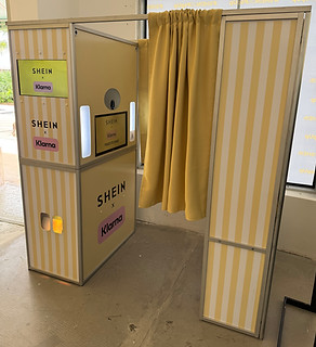 Branded enclosed booth for SHEIN and Klarna featuring yellow striped panels and a privacy curtain, designed for fashion events and experiential marketing.