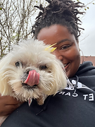 a smiling woman holding a small white puppy with its tongue sticking out