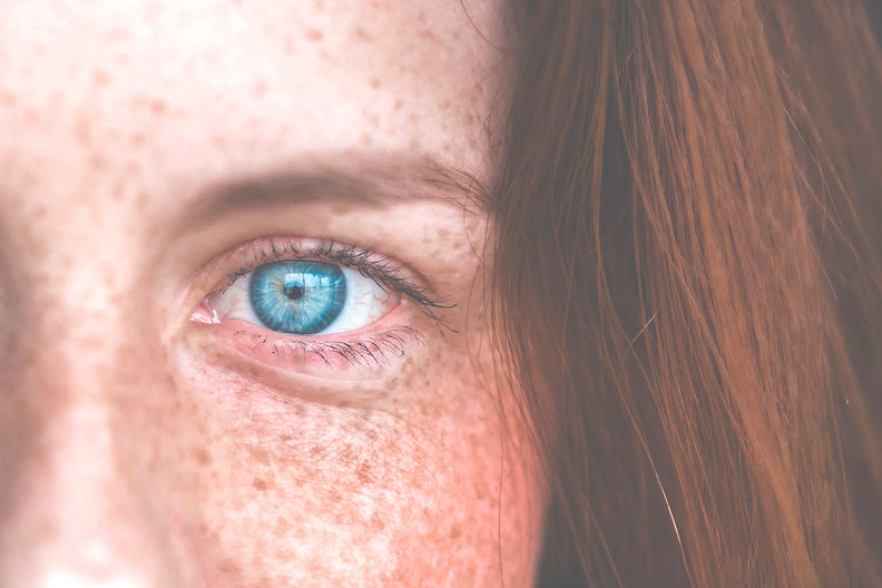 A young red haired girl blue and green eye close-up