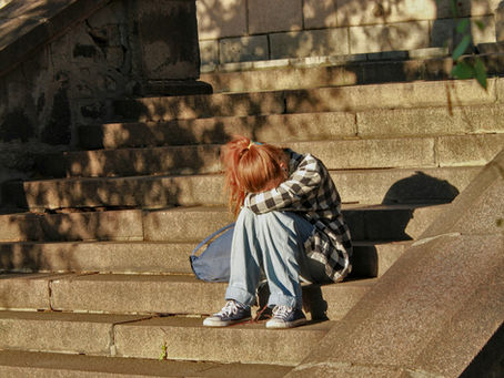 Girl sitting on steps with her head in her arms, crying