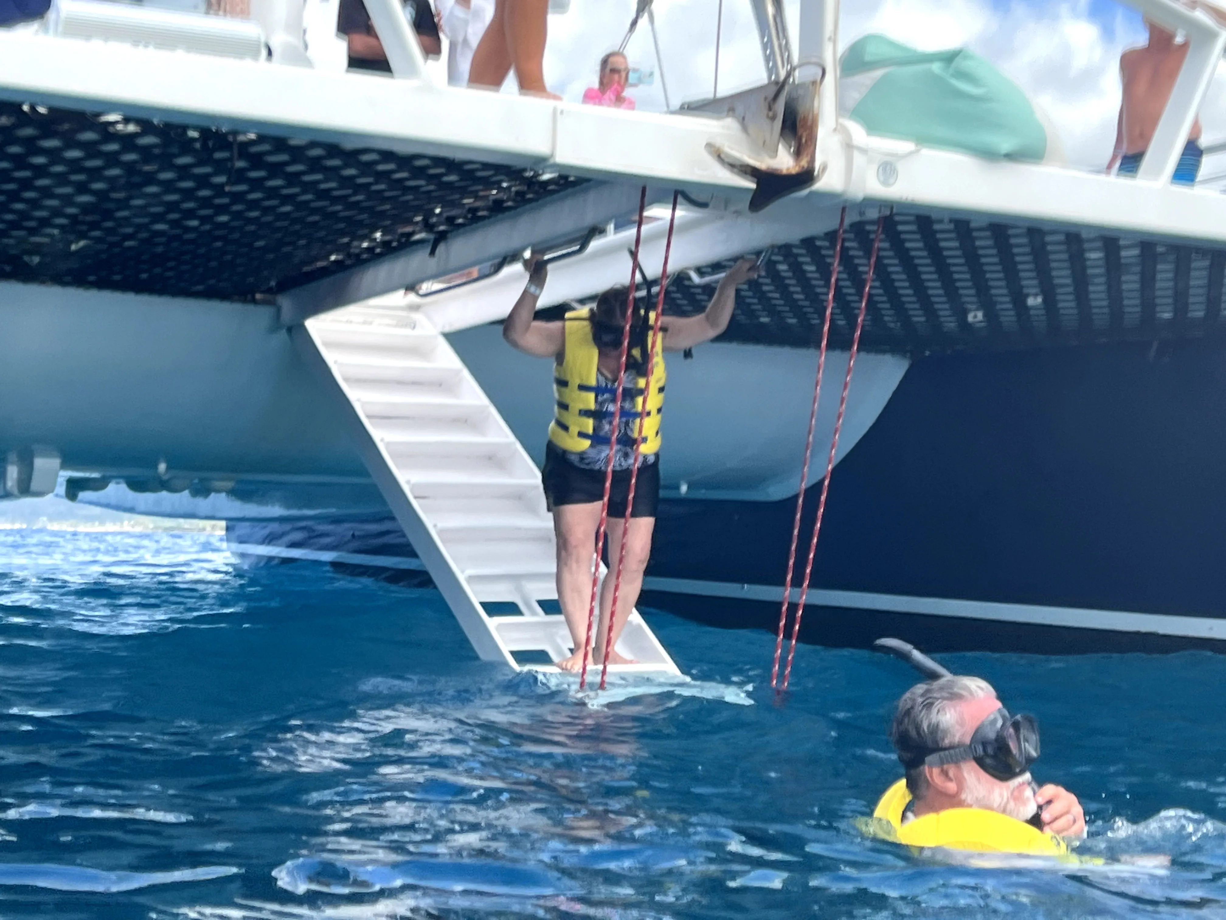 Person getting into water from boat to go snorkeling in Hawaii, Ko Olina Ocean Adventures.