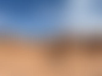 Panoramic view of the iconic hoodoo rock formations at Goblin Valley State Park in Utah, with clusters of rounded, mushroom-shaped red sandstone structures under a bright blue sky with wispy clouds.
