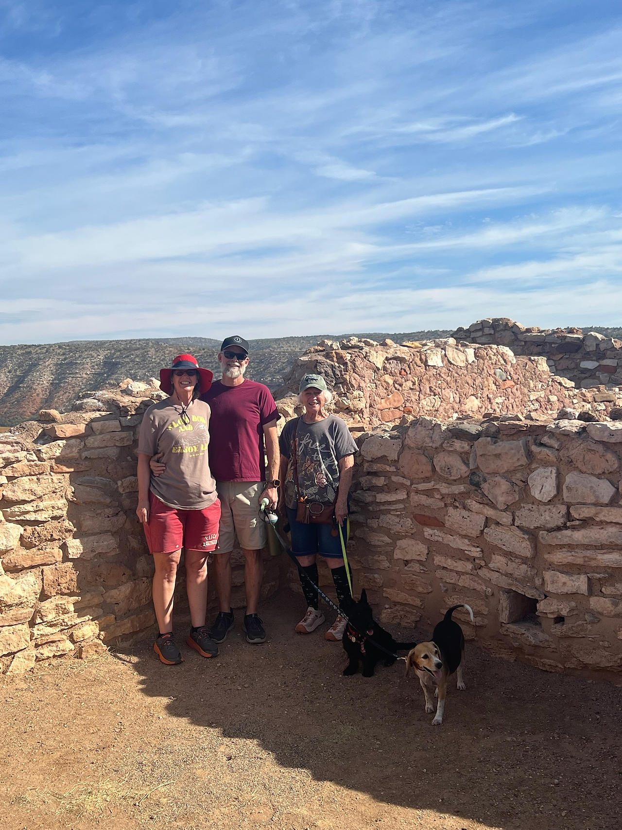 Family photo at Tuzigoot National Monument near Clarkdale, Arizona — travelers posing with their dogs among ancient Sinagua stone ruins during The TinMan Adventures Utah to Arizona road trip.