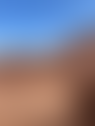 A person standing among the unique red sandstone hoodoo formations at Goblin Valley State Park in Utah, surrounded by rounded rock shapes under a vivid blue sky.