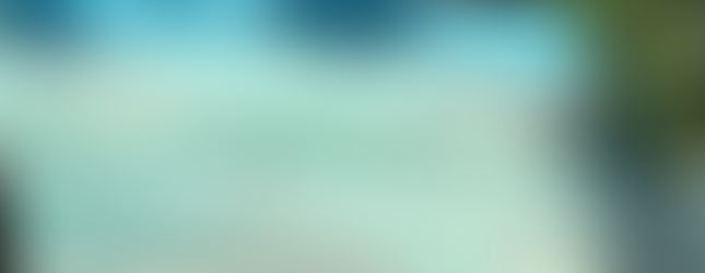 Informative sign titled "Life in the Wetland," describing the various kinds of plant and animal life supported by wetland ecosystems. The sign features illustrations of wetland wildlife, including birds and aquatic plants, and includes detailed text about the ecological importance of cattails, treetops, and mudflats. The sign is partially shaded by tree branches.