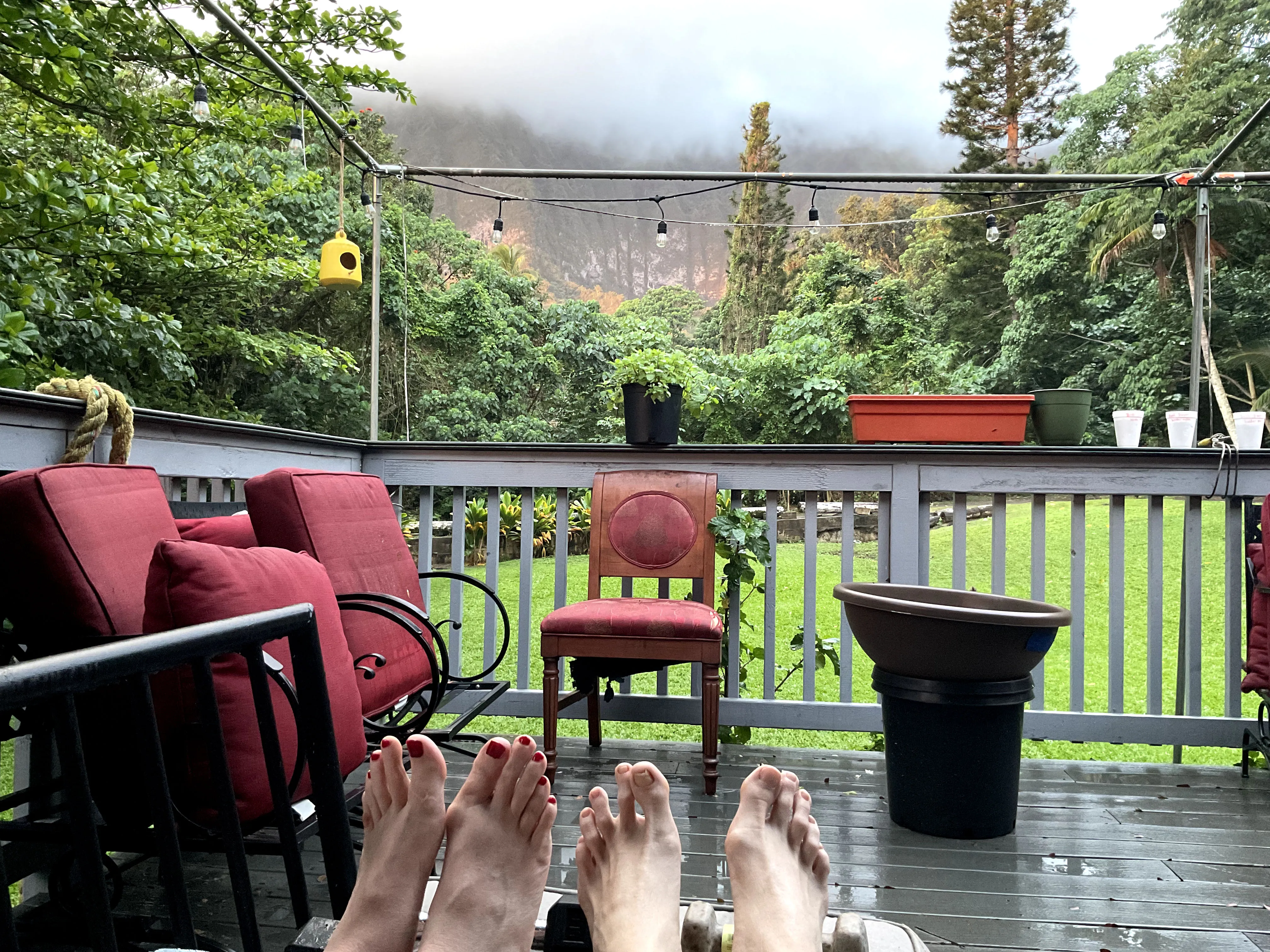 Patio with red furniture with clouds covering the tops of a mountain.