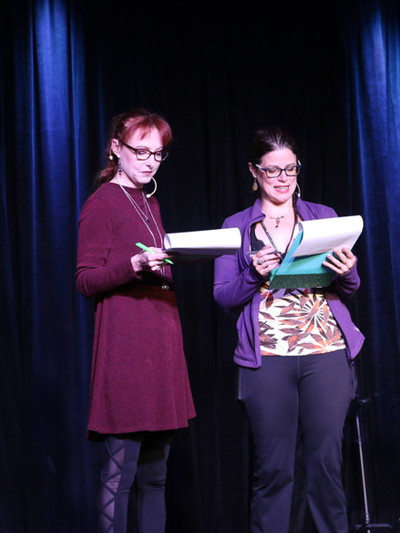 2 people hosting on stage while a person plays guitar