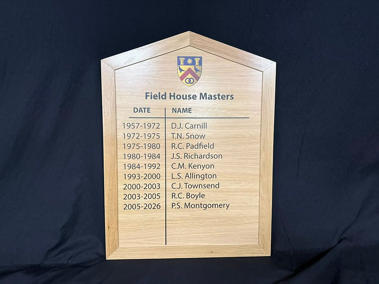 Angled detail of Dean Close House Field House Masters wooden honours board showing crest, date and name columns.