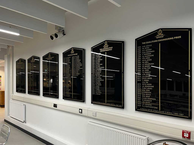 Black and gold School honours boards on a white hallway wall