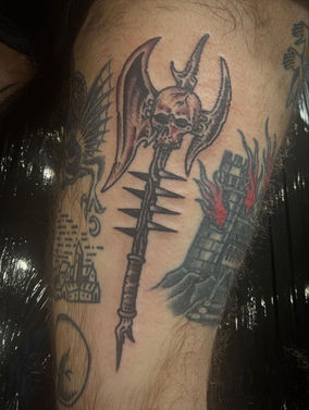 Traditional tattoo of a winged axe with a skull motif.
