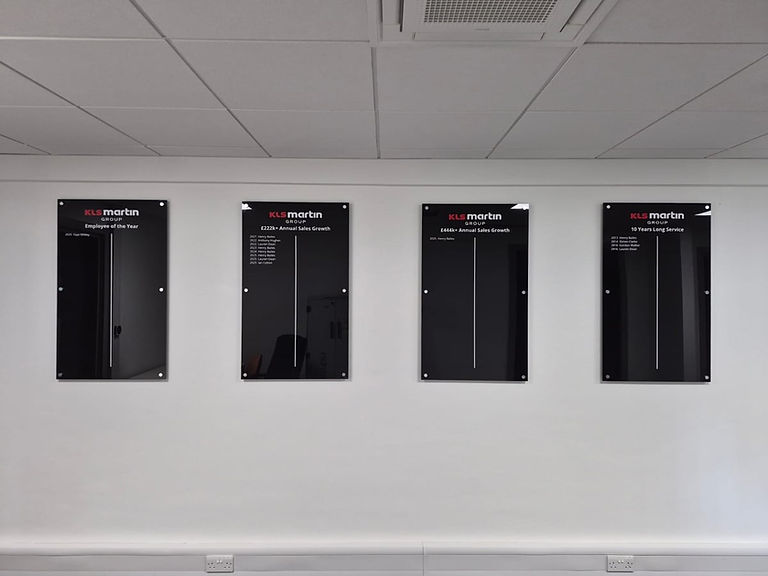 KLS Martin Group acrylic honours boards showing all four black panels with red branding installed on a white office wall.
