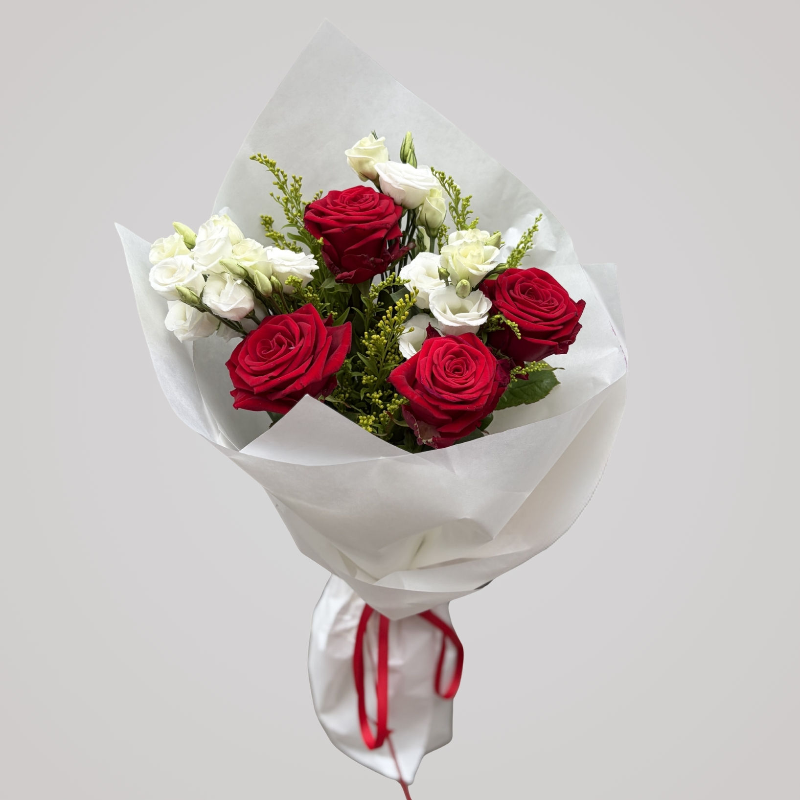Elegant buket med røde premiumroser, hvid lisianthus og sæsongrønt håndbundet i skandinavisk stil af Florén.