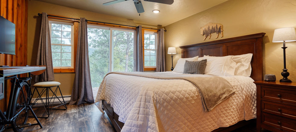 King bed with views of pine trees and wildlife at Highland Meadows Resort cabin in South Dakota.