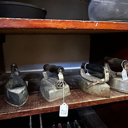 Four flatirons in an antique store. These are the types of flat irons typically used in hotels and other lodging establishments.