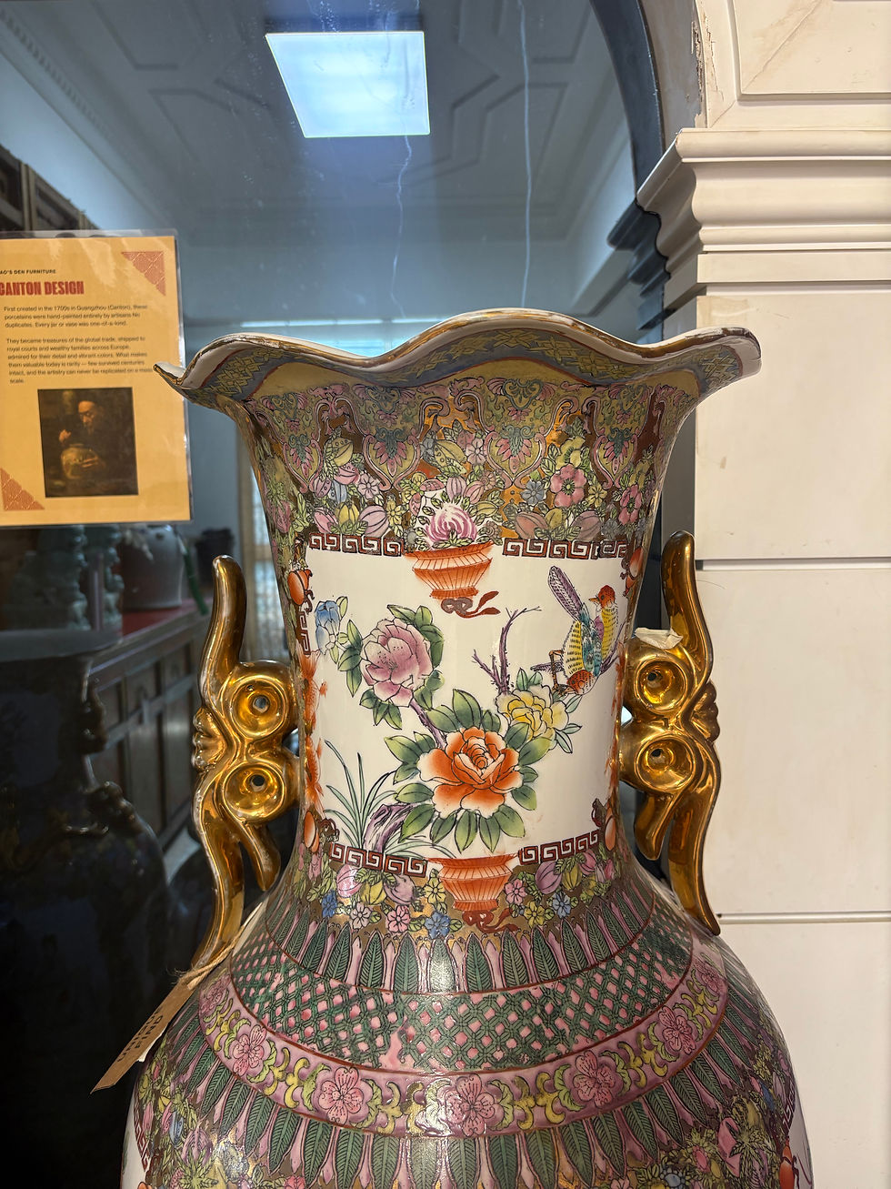 Close-up of Canton porcelain vase rim with floral decoration and ornate gold-painted handles.