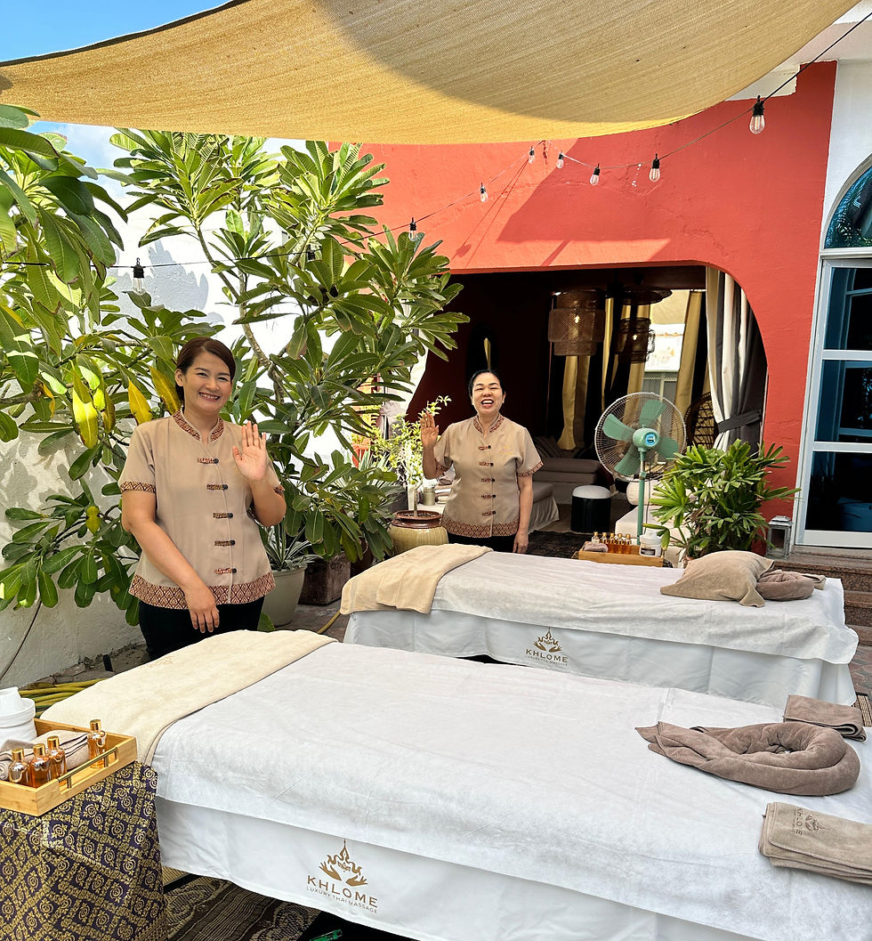 Khlome Thai massage therapist preparing a home massage bed in a luxury Dubai apartment during summer, with travel luggage, children’s toys, groceries, and warm sunlight showing a busy family lifestyle.