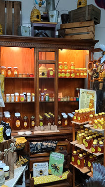 Wooden display case filled with honey jars, Bee products, and fresh produce.