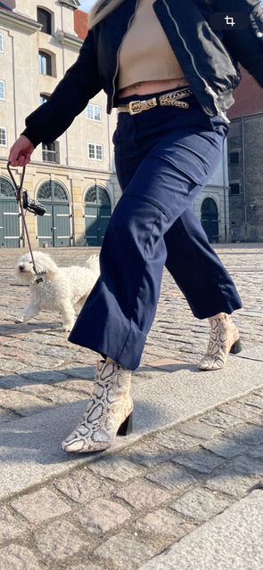 Close up of a woman wearing pants and walking a dog.